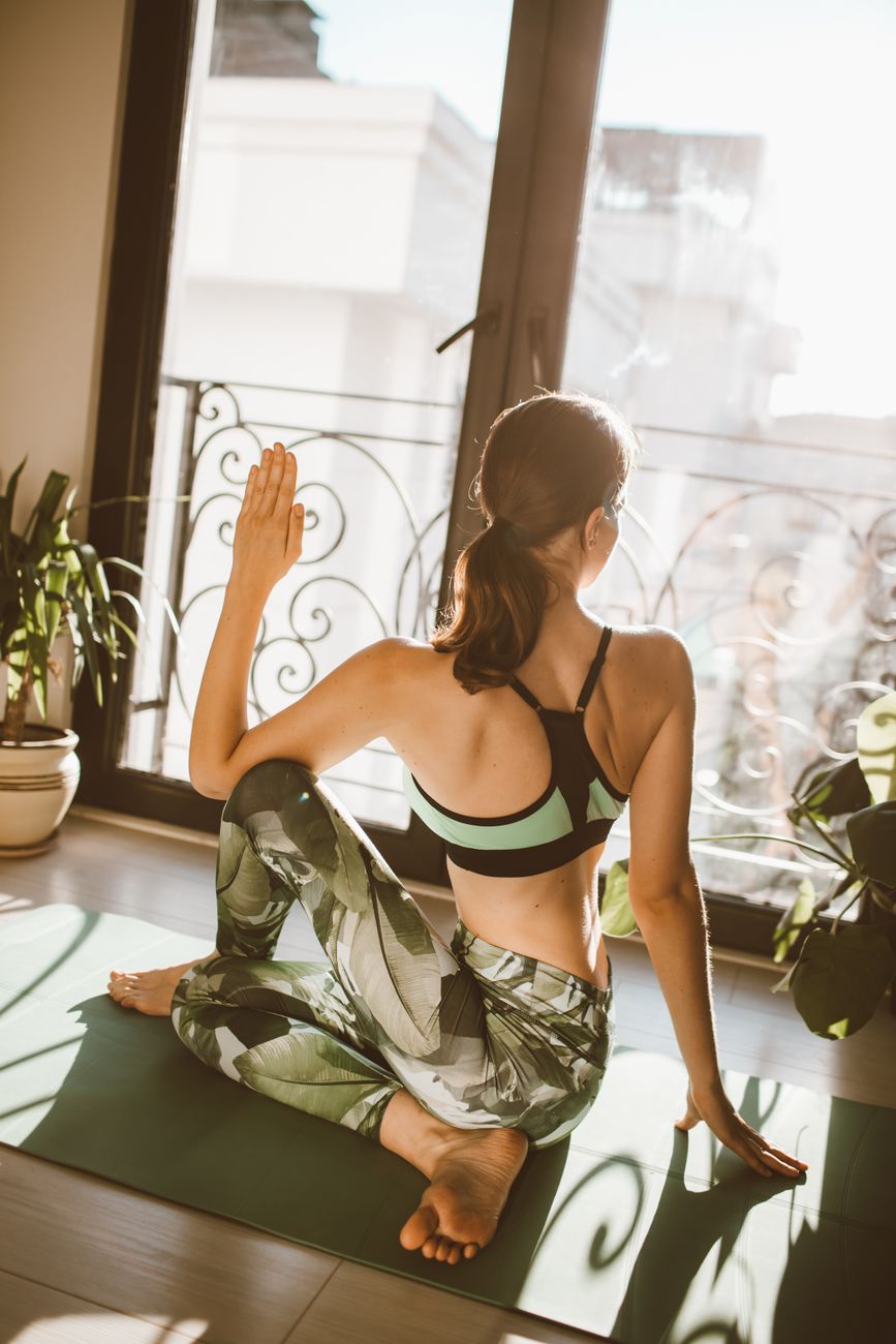 Mulher praticando yoga em casa com luz natural